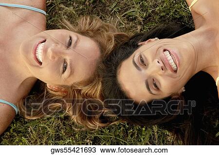 Stock Image - High angle view of a mid adult woman with a mature woman lying on the grass. Fotosearch