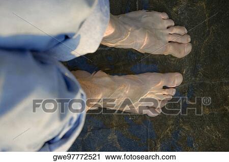 Stock Image - High angle view of a person ankles deep in water. Fotosearch