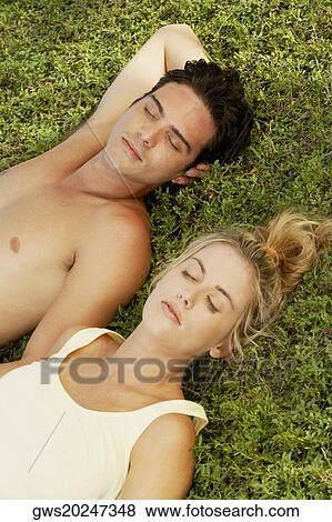 Stock Photo - High angle view of a young couple lying on the lawn. Fotosearch