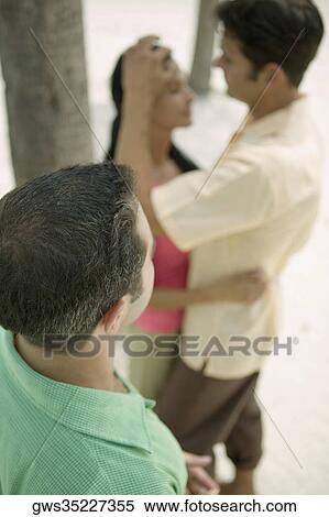 High angle view of a young man looking at a young couple embracing each other View Large Photo Image Stock Photography - High angle view of a young man looking at a young couple embracing each other. Fotosearch