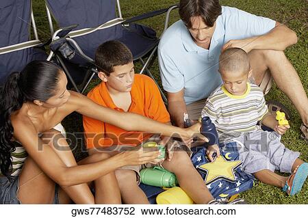 High angle view of a young woman and a mid adult man sitting on the grass with their two children View Large Photo Image Stock Image - High angle view of a young woman and a mid adult man sitting on the grass with their two children. Fotosearch