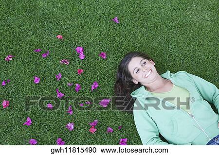 Stock Image - High angle view of a young woman lying on the grass. Fotosearch