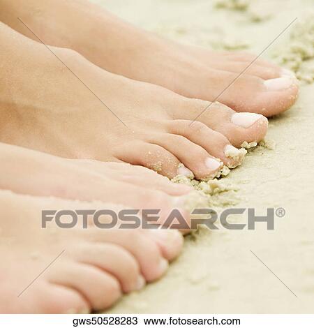 High angle view of the feet of two people on sand View Large Photo Image Stock Image - High angle view of the feet of two people on sand. Fotosearch