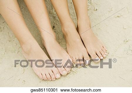 High angle view of the feet of two people on sand View Large Photo Image Stock Image - High angle view of the feet of two people on sand. Fotosearch