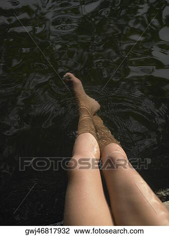 Stock Image - High angle view of woman's legs in water. Fotosearch