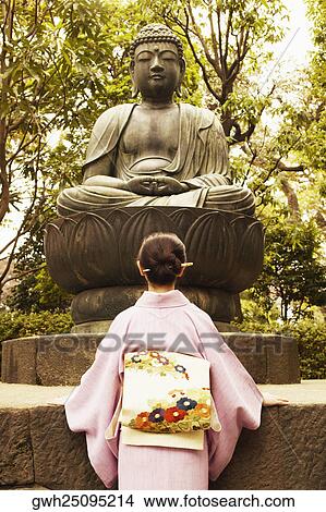 Low angle view of a mature woman in front of a statue of Buddha View Large Photo Image Picture - Low angle view of a mature woman in front of a statue of Buddha . Fotosearch