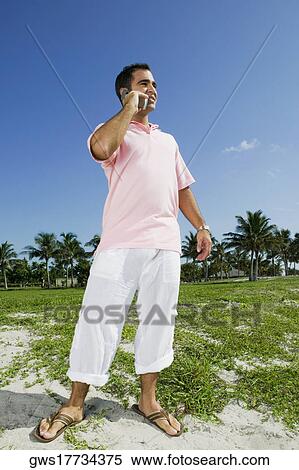 Low angle view of a young man talking on a mobile phone View Large Photo Image Stock Photography - Low angle view of a young man talking on a mobile phone. Fotosearch