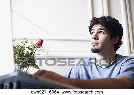 Low angle view of a young man thinking View Large Photo Image Picture - Low angle view of a young man thinking. Fotosearch