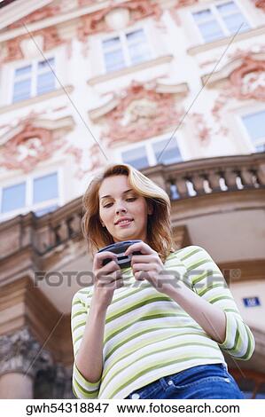 Low angle view of a young woman holding a mobile phone View Large Photo Image Stock Photo - Low angle view of a young woman holding a mobile phone . Fotosearch