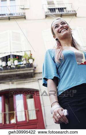 Low angle view of a young woman standing in front of a building View Large Photo Image Stock Image - Low angle view of a young woman standing in front of a building . Fotosearch