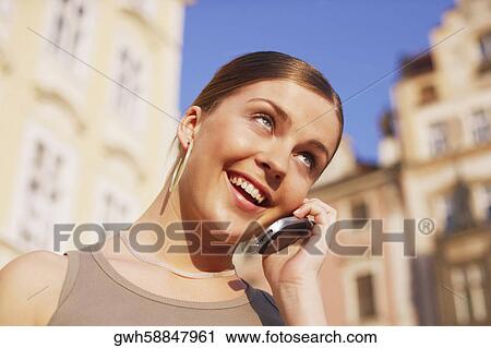 Low angle view of a young woman talking on a mobile phone View Large Photo Image Stock Image - Low angle view of a young woman talking on a mobile phone . Fotosearch