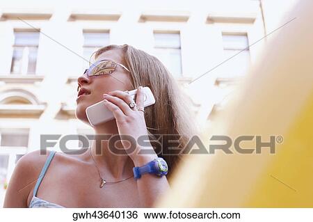 Low angle view of a young woman talking on a mobile phone View Large Photo Image Stock Photograph - Low angle view of a young woman talking on a mobile phone . Fotosearch