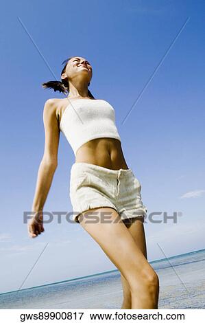 Low angle view of a young woman walking on the beach View Large Photo Image Stock Photo - Low angle view of a young woman walking on the beach. Fotosearch