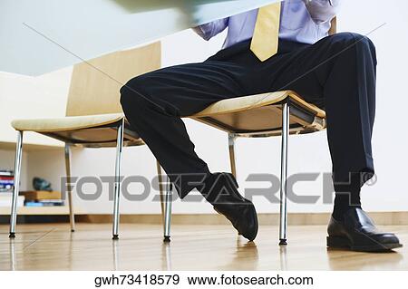 Stock Photo - Low section view of a businessman sitting in an office. Fotosearch