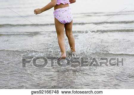 Low section view of a girl wading in water on the beach View Large Photo Image Stock Photo - Low section view of a girl wading in water on the beach. Fotosearch