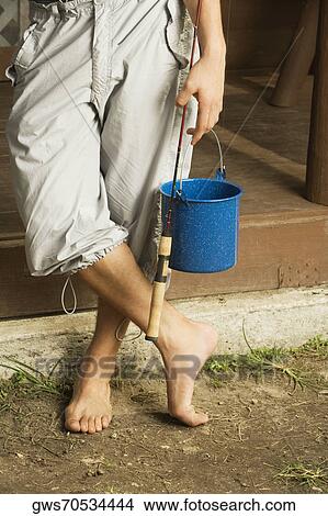 Low section view of a man holding a fishing rod and a bucket View Large Photo Image Picture - Low section view of a man holding a fishing rod and a bucket. Fotosearch