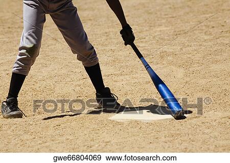 Stock Photo - Low section view of a man holding a baseball bat. Fotosearch