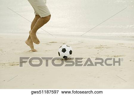 Low section view of a man playing with a soccer ball on the beach View Large Photo Image Stock Photo - Low section view of a man playing with a soccer ball on the beach. Fotosearch