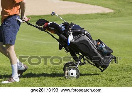 Stock Image - Low section view of a man pulling a golf bag. Fotosearch