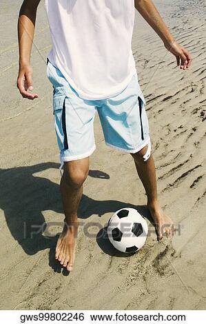 Low section view of a person playing with a soccer ball on the beach View Large Photo Image Stock Photograph - Low section view of a person playing with a soccer ball on the beach. Fotosearch