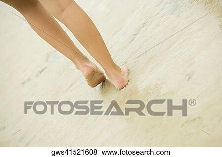 Low section view of a person walking on sand View Large Photo Image Stock Photo - Low section view of a person walking on sand. Fotosearch