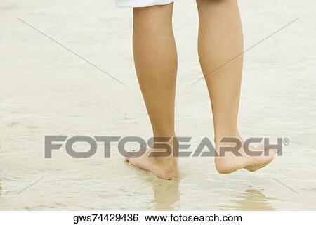 Low section view of a person walking on sand View Large Photo Image Stock Photograph - Low section view of a person walking on sand. Fotosearch