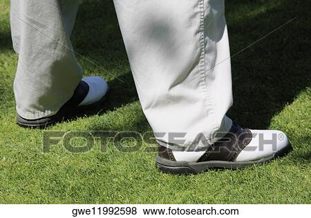 Stock Photo - Low section view of a person wearing golf shoes. Fotosearch