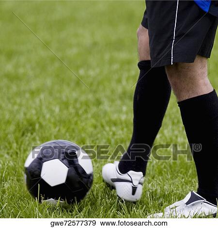 Stock Photo - Low section view of a soccer player with a soccer ball. Fotosearch