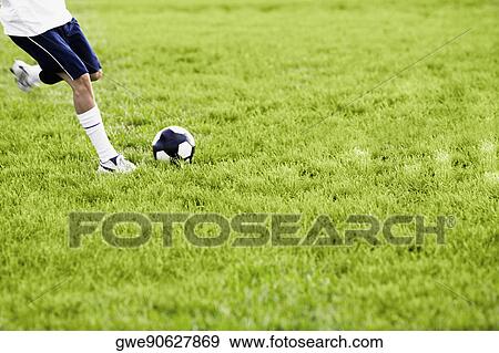 Stock Photo - Low section view of a soccer player kicking a soccer ball. Fotosearch