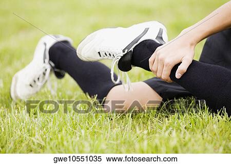 Stock Photography - Low section view of a soccer player holding his leg. Fotosearch