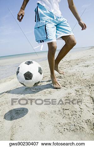 Low section view of a teenage boy playing with a soccer ball on the beach View Large Photo Image Stock Photo - Low section view of a teenage boy playing with a soccer ball on the beach. Fotosearch