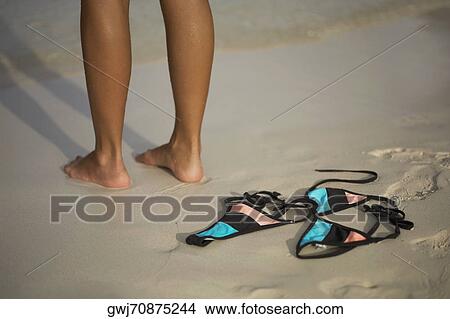 Low section view of a woman standing on the beach near a bikini View Large Photo Image Picture - Low section view of a woman standing on the beach near a bikini. Fotosearch