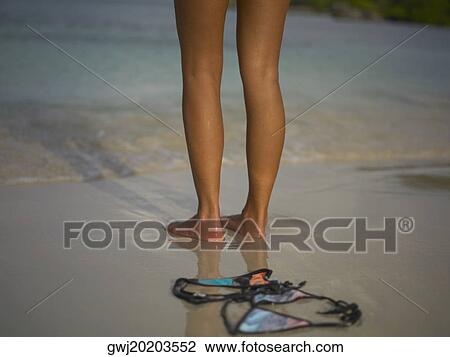 Low section view of a woman standing on the beach near a bikini View Large Photo Image Stock Image - Low section view of a woman standing on the beach near a bikini. Fotosearch