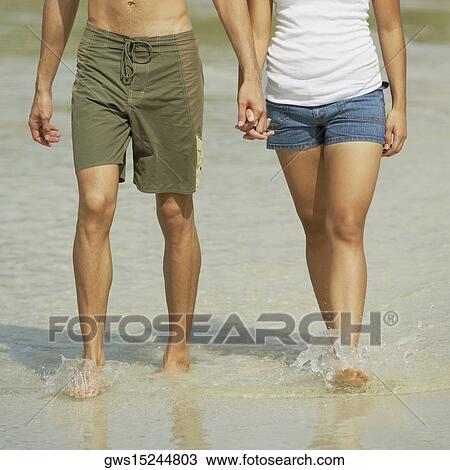 Low section view of a young couple holding hands and walking on the beach View Large Photo Image Stock Image - Low section view of a young couple holding hands and walking on the beach. Fotosearch