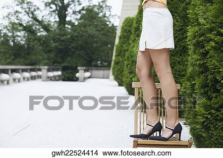 Low section view of a young woman standing on a chair View Large Photo Image Picture - Low section view of a young woman standing on a chair . Fotosearch