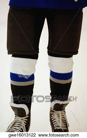 Stock Image - Low section view of an ice hockey player wearing ice skates. Fotosearch