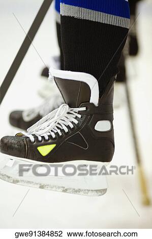 Stock Image - Low section view of an ice hockey player with an ice hockey stick. Fotosearch