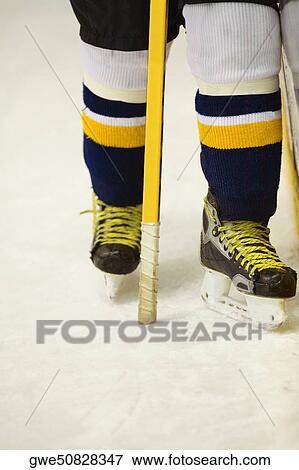 Stock Photo - Low section view of an ice hockey player with an ice hockey stick. Fotosearch