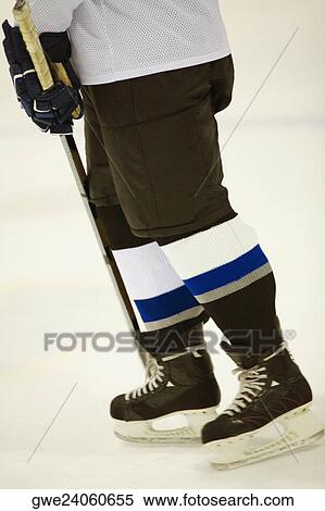 Stock Photography - Low section view of an ice hockey player holding an ice hockey stick. Fotosearch