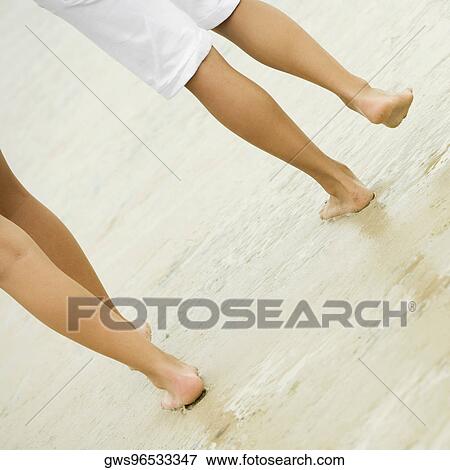 Low section view of two people walking on the beach View Large Photo Image Stock Photo - Low section view of two people walking on the beach. Fotosearch