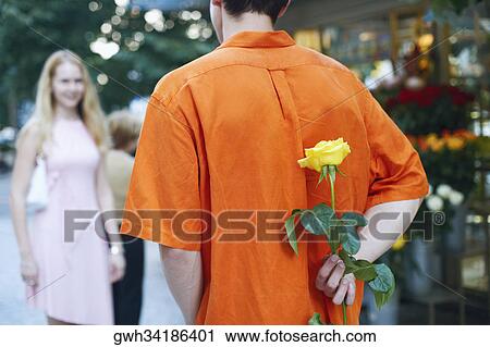 Man hiding a flower behind his back View Large Photo Image Stock Image - Man hiding a flower behind his back . Fotosearch