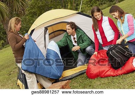 Stock Photo - Mature man and a mid adult woman camping with their two daughters. Fotosearch