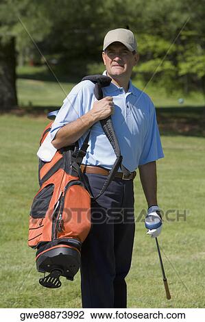 Mature man standing on a golf course carrying a golf bag with a golf club View Large Photo Image Stock Image - Mature man standing on a golf course carrying a golf bag with a golf club. Fotosearch