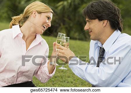 Picture - Mid adult man and a young woman holding champagne flutes. Fotosearch