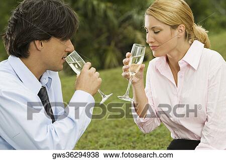 Mid adult man and a young woman drinking champagne View Large Photo Image Stock Photo - Mid adult man and a young woman drinking champagne. Fotosearch