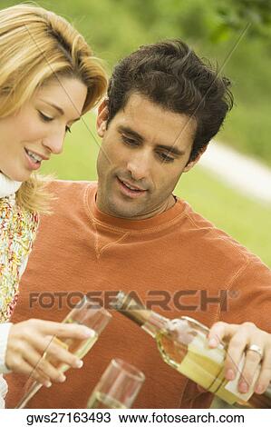 Stock Image - Mid adult man pouring champagne into a champagne flute. Fotosearch