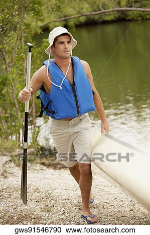 Mid adult man pulling a canoe View Large Photo Image Stock Image - Mid adult man pulling a canoe. Fotosearch
