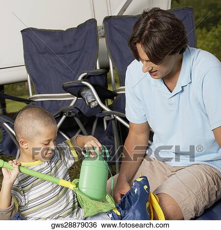 Mid adult man sitting with his son holding a butterfly net View Large Photo Image Stock Photograph - Mid adult man sitting with his son holding a butterfly net. Fotosearch