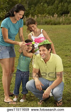 Mid adult woman and her two daughters putting butterfly nets on a mid adult man's head View Large Photo Image Stock Photo - Mid adult woman and her two daughters putting butterfly nets on a mid adult man's head. Fotosearch