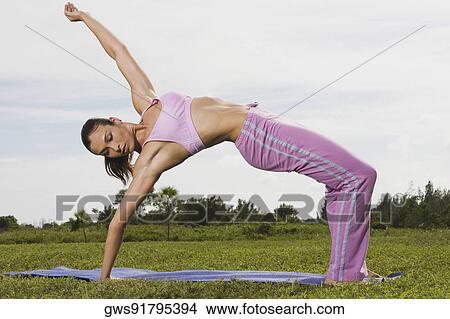 Picture - Mid adult woman bending over backwards. Fotosearch